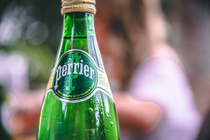 upper half close up of Perrier glass bottle filled with liquid