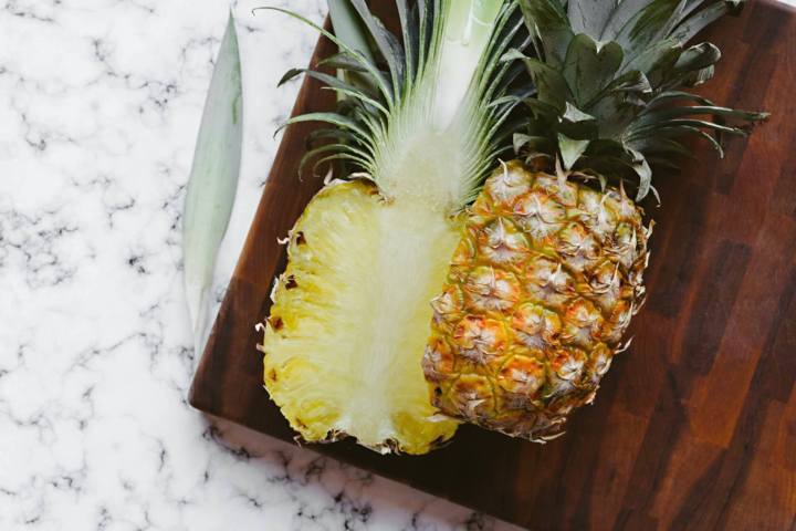 pineapple slice in half placed on a wooden board on a marble surface