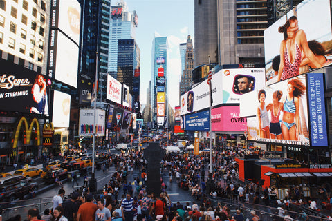 Intersection full of pedestrians and advertisements overhead