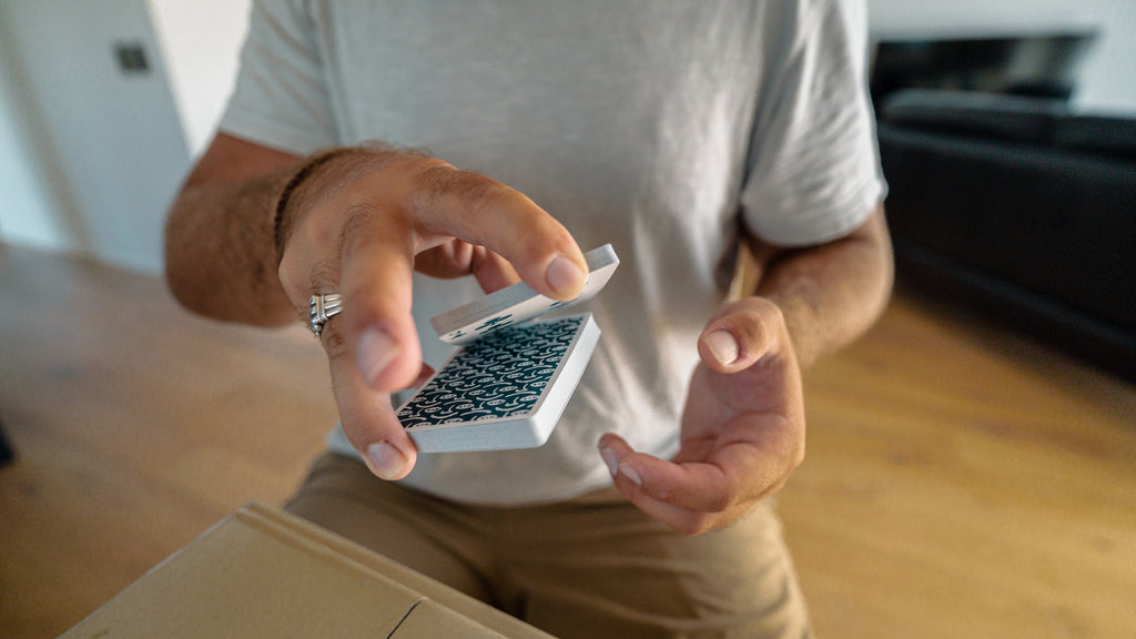 Person performing a cardistry cut in one hand, splitting the packet in two