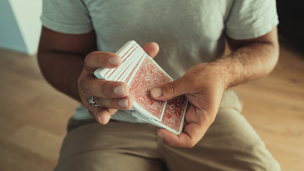 Person shuffling red deck of playing cards using the overhand shuffle technique