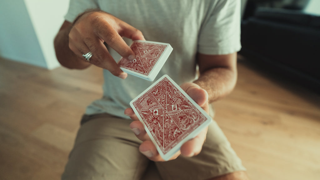 A person performing a shuffle with a deck of red playing cards