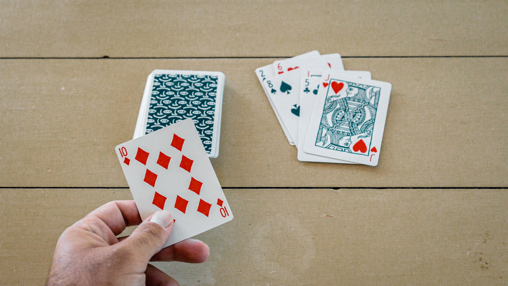 Someone playing High or Low with a deck of playing cards on a wooden surface
