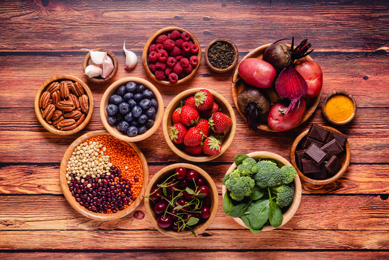 Antioxidant-rich-foods-beans-berries-nuts-vegetables-chocolate-in-bowls-on-wood-table
