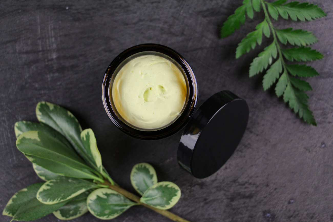 rebirth-body-butter-lid-off-to-display-texture-with-greenery-flatlay