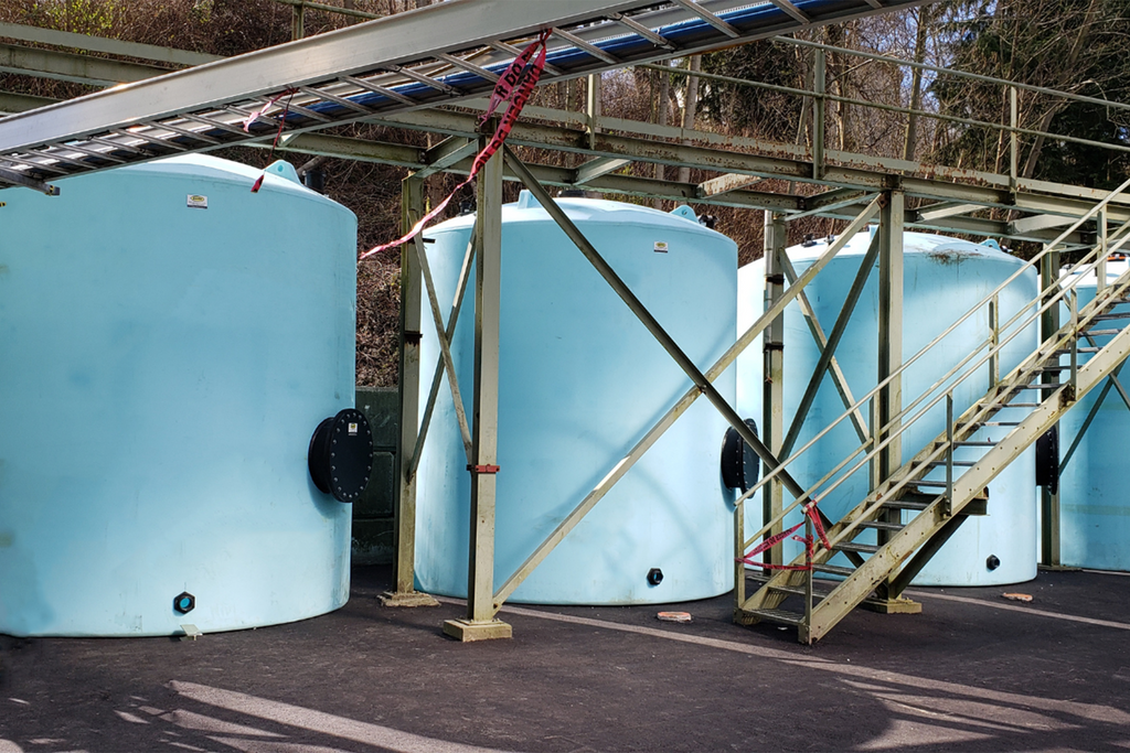 Picture of 4 vertical blue plastic tanks. All are fitted with custom manways.