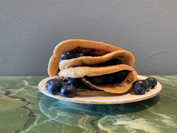 A stack of pancakes with blueberries in between the layers
