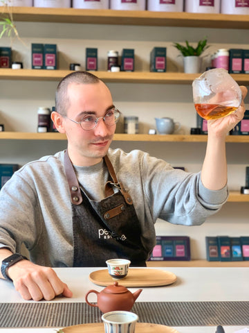 a photograph of a man observing the colour of tea in a glass carafe