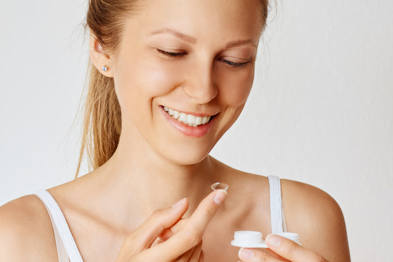 Happy woman holding a contact lens.