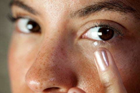 A woman inserting a contact lens to experience the benefits of Bausch and Lomb contact lenses.