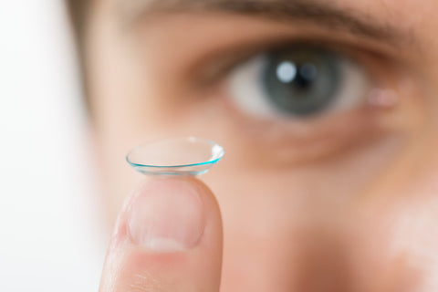 A man holding a piece of contact lens.