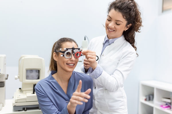 Optometrist changes lenses in trial frame to examine the vision of young woman patient.