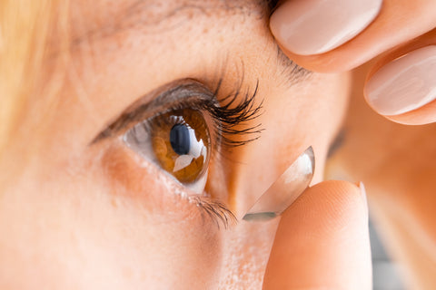 Close up shot of a woman inserting a contact lens in her eyes.