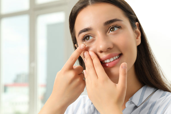 Woman putting a contact lens in her sensitive eye.