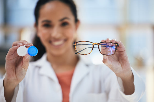 Optometrist holding a contact lens and a glass on both hands.
