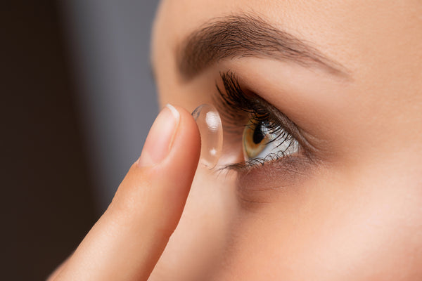 A woman holds contact lens on her finger ready to wear.