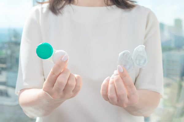 A woman holding contact lenses.