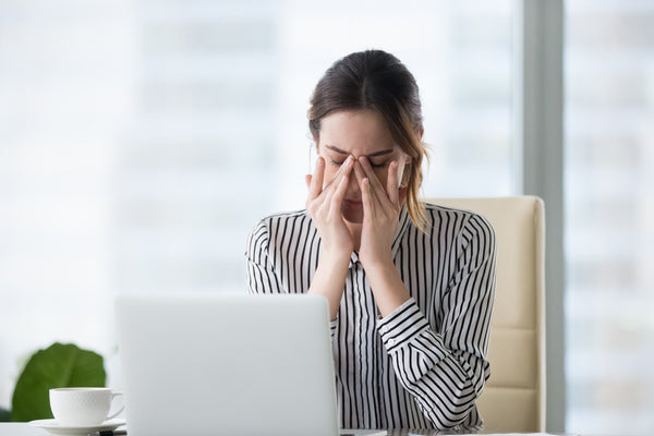 Tired woman feeling eye strain and dry eyes while holding her closed eyes.