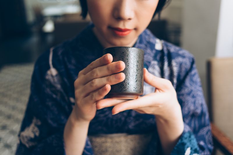 A woman preparing tea for the Tea Ceremony after mastering the art of mindful tea drinking.