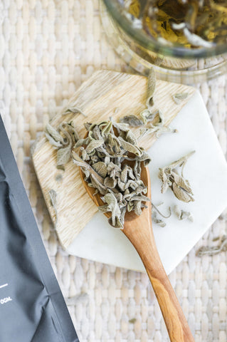 Dried sage tea in a wooden spoon.