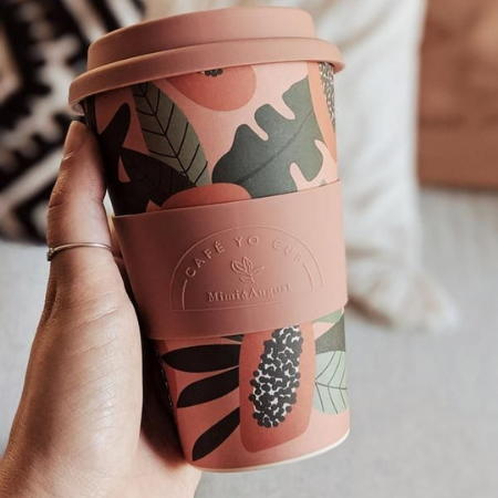 Woman holding a pink and green keep cup