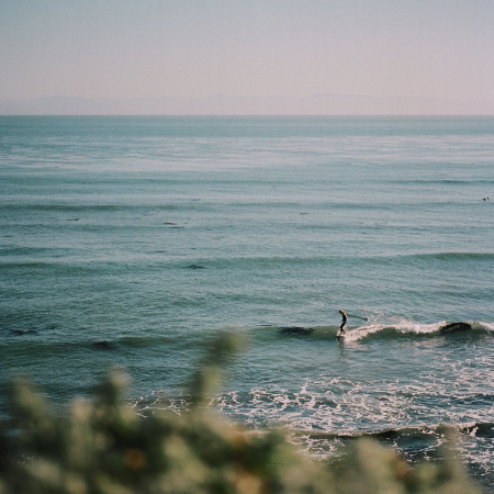 Horizon view of the ocean at dusk with a single surfer in the waves