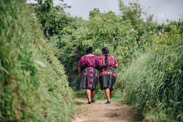 Two indigenous Maya women in their huipiles and cortes walking through the Guatemala forest