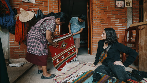 An Artisan in Mexico showing Ali the rugs they made.