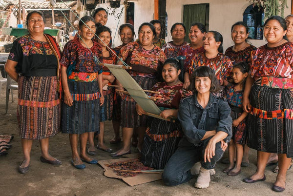 Artisans in Guatemala taking a photo with Ali. One is holding a backstrap.