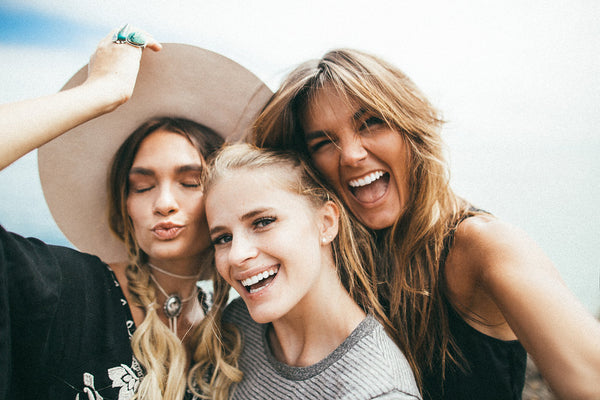 Three female friends smiling at the camera while taking a selfie.