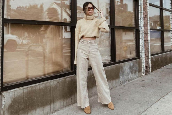 woman in a monochromatic cream outfit modeling outside in a downtown city street.