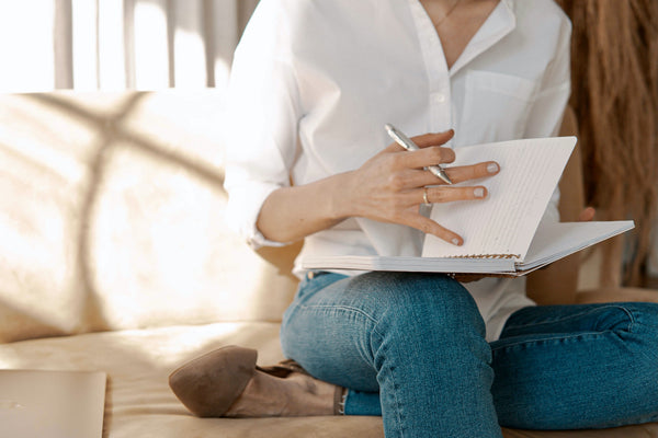 woman looking through her journal on a couch maybe getting ready to write.