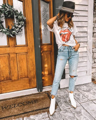 Graphic band tee paired with distressed jeans and white western booties