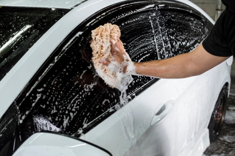 Vehicle Cleaning Concept - a man scrubing a car