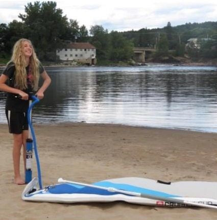 A small female struggling to inflate an inflatable stand up paddle board