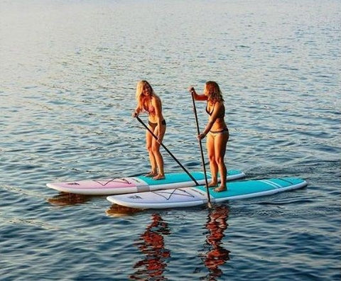Two women stand up paddle boarding 