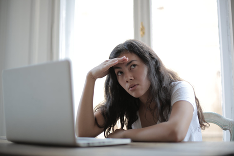 Woman sitting in front of computer holding her head.
