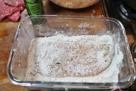Breading the marinated chicken in the seasoned flour prior to frying