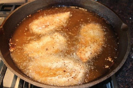 Chicken breasts just added to the hot oil, before being turned over.