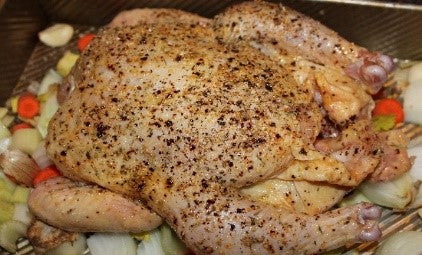 Whole chicken on a bed of mirepoix.