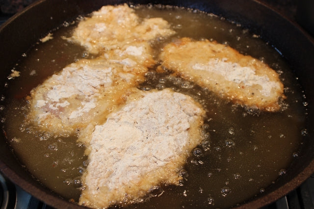 Chicken just placed into the frying oil, before being turned.