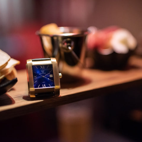 Square watch with blue dial and gold case from SÖNER - close up on shelf