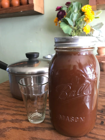 a jar of homemade chai concentrate with an empty cup to it's left