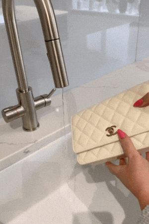 Holding our brand new Chanel handbag under a running tap!