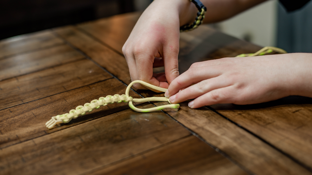 Young kid weaving a paracord bracelet