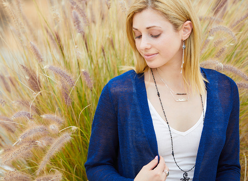 jewelry model wearing beaded necklace and sterling chain in front of cat tail bush 