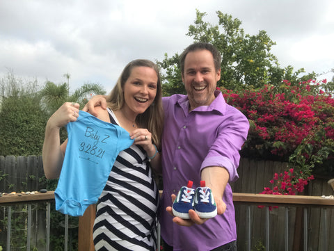 Nikki & husband Rob holding up baby boy Z's onesie and vans to announce his arrival on 3/28/21