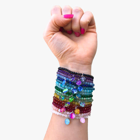arm stacked with all the illness and disease awareness bracelets in a rainbow of colors