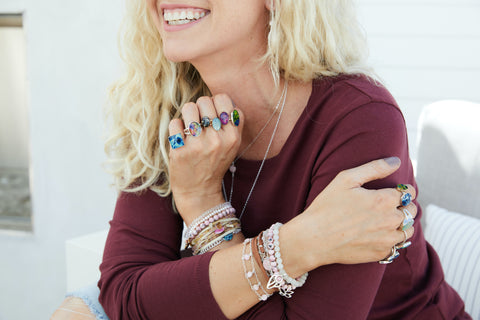 model wearing lots of legacy jewelry rings and bracelets that give back to cancer research