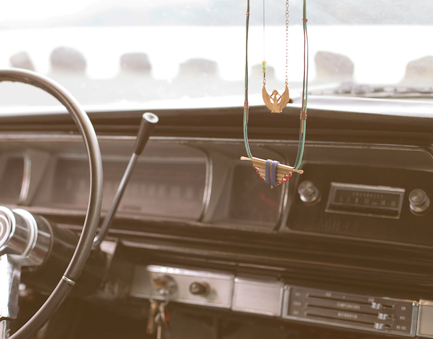 Two necklaces dangle on a rearview mirror.